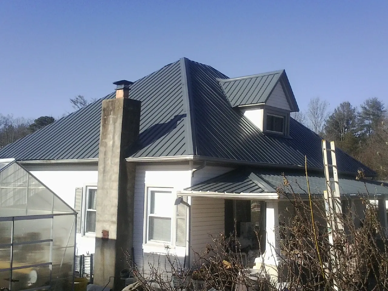Dark blue standing seam metal roof on a white farmhouse with dormer — Slate & Tile Roof Repair by Roofing Brothers in Waring