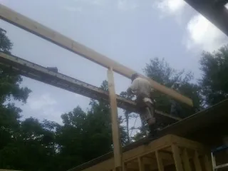 Carpenter setting a ridge beam over a new addition frame — Ice Dam Removal by Roofing Brothers in Waring