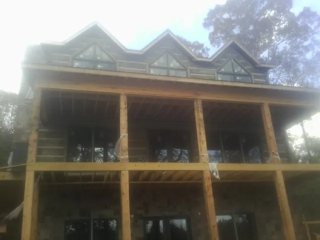 Dormers and porch framing on a large log home under construction — Roof Coating work by our crew in Waring