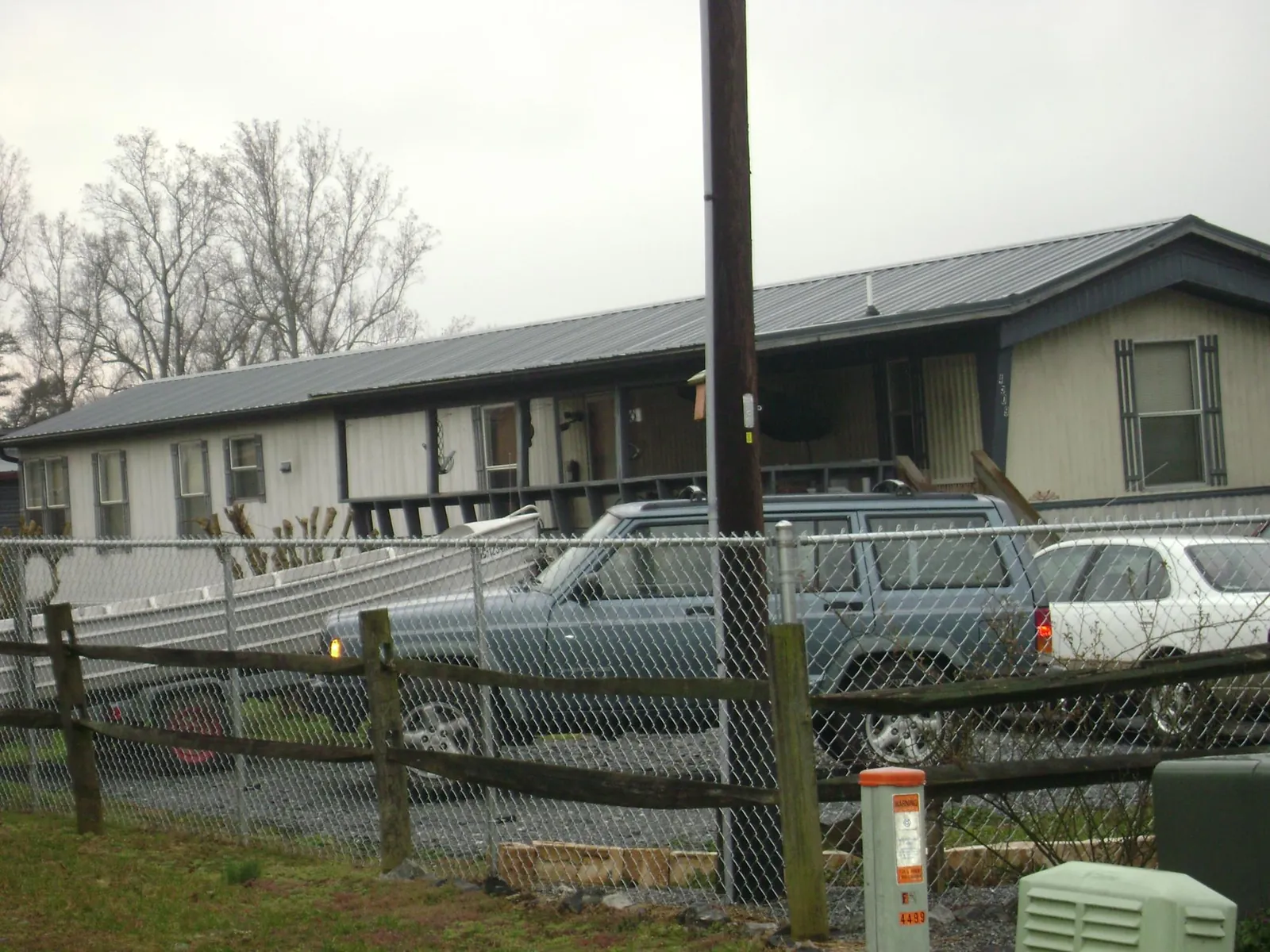Dark metal roof on a long single story building behind a chain link fence in Waring